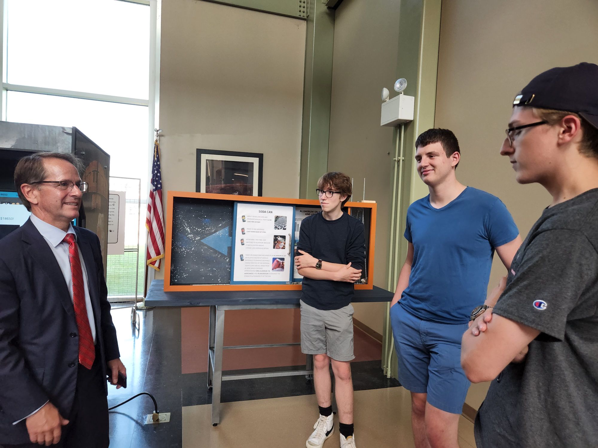Frank Edelblut talks to SST students David Busnel, Grant Sorber, and Christian Hanson about SST's aluminum mining exhibit