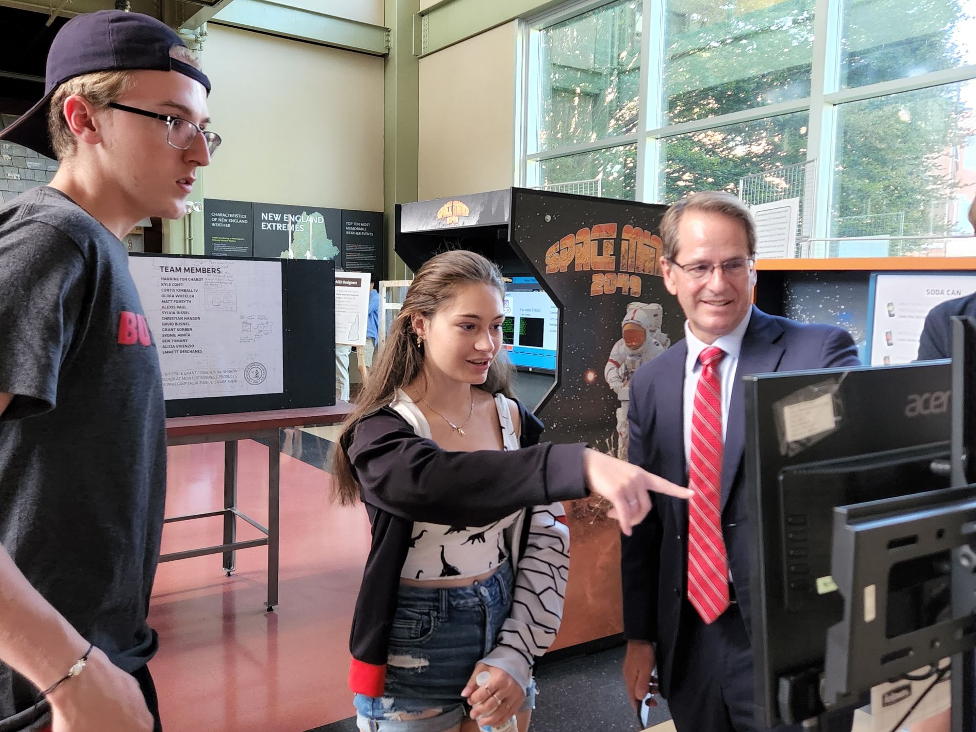 MSDC/Seacoast School of Technology student Olivia Wheeler explains a feature of the Power Sources in Space exhibit to Frank Edelblut